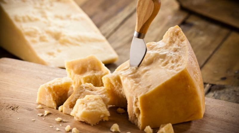 Scaglie di Parmigiano Reggiano stagionato con coltello da formaggio su tagliere rustico, pronte per la degustazione a Milano