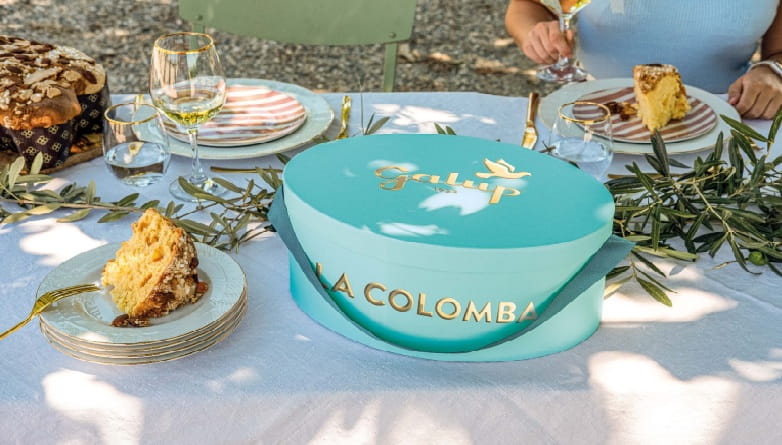 Pasqua 2026 Galup, Colomba in elegante cappelliera turchese su tavola apparecchiata all’aperto in primavera, eccellenza piemontese