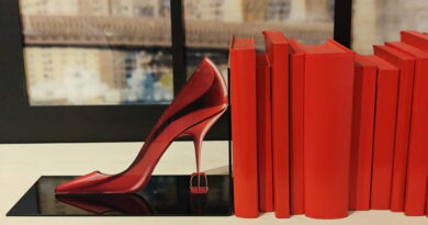 Scarpa rossa con tacco alto accanto a libri coordinati, simbolo di moda e stile nel film Il diavolo veste Prada 2 ambientato tra Milano e scenari internazionali