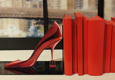 Scarpa rossa con tacco alto accanto a libri coordinati, simbolo di moda e stile nel film Il diavolo veste Prada 2 ambientato tra Milano e scenari internazionali