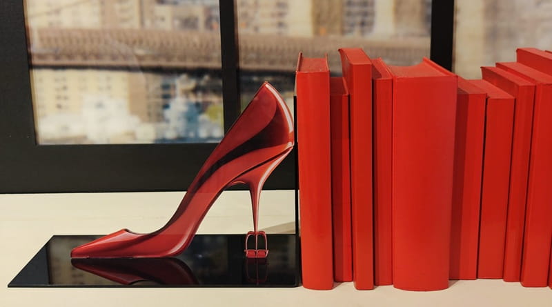 Scarpa rossa con tacco alto accanto a libri coordinati, simbolo di moda e stile nel film Il diavolo veste Prada 2 ambientato tra Milano e scenari internazionali