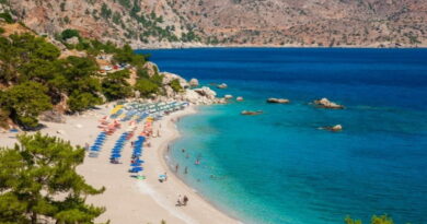 Spiaggia di Karpathos con mare cristallino e ombrelloni, vacanza a Karpathos agosto tra relax e natura incontaminata