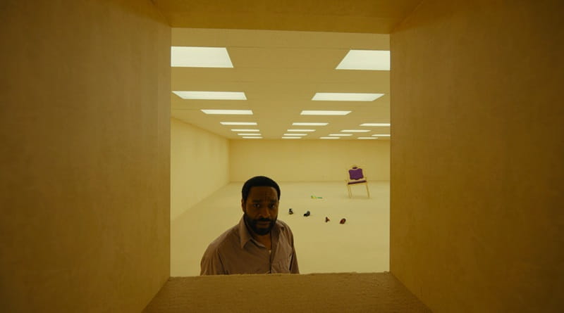 Scena del film horror Backrooms con un uomo intrappolato in una misteriosa stanza dai corridoi infiniti illuminati da neon.