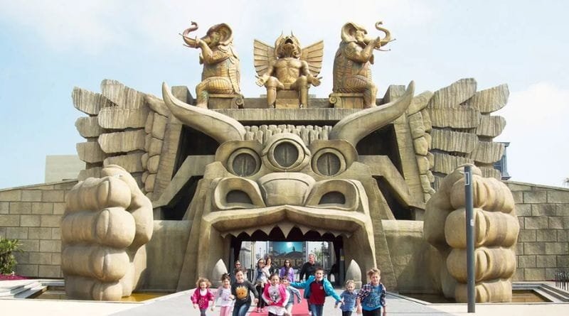 Ingresso scenografico di un'attrazione di Cinecittà World Roma con famiglie e bambini in visita al parco divertimenti.