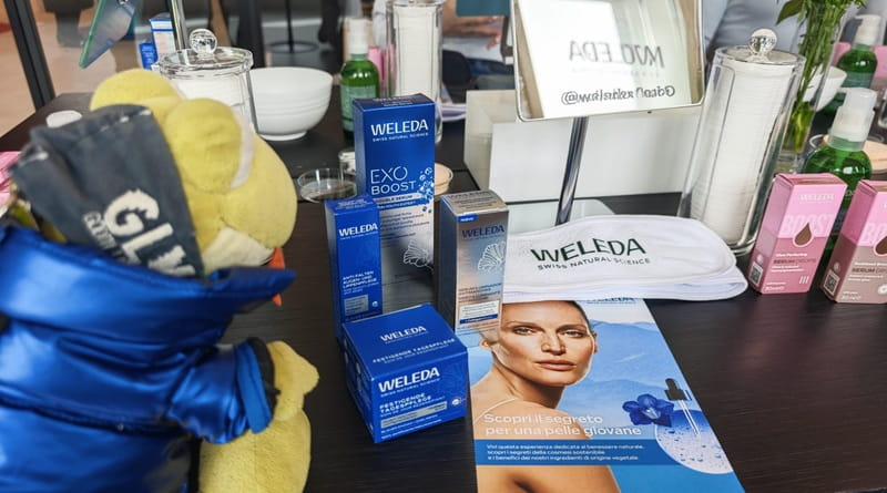 Geco Gaudenzio osserva prodotti Weleda skincare naturale Exo Boost durante evento benessere per pelle luminosa