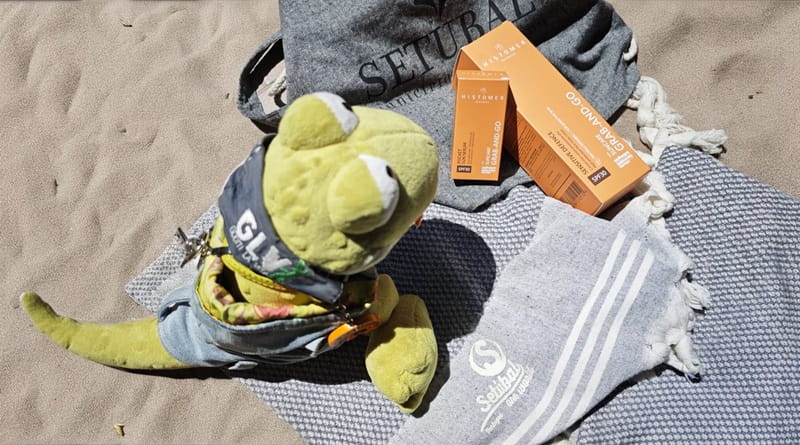 Geco Gaudenzio in spiaggia con il solare Histomer Sun Film SPF 30 appoggiato sul telo mare durante una giornata di vacanza.
