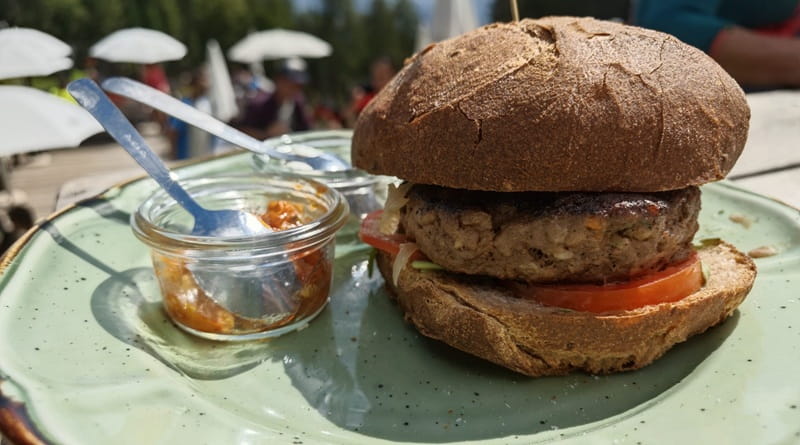 Hamburger di cervo servito a Malga Rina, in Alto Adige, con pane rustico e contorno, protagonista della sosta del Geco dopo la salita.