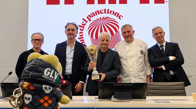 Iginio Massari durante la conferenza stampa della Coppa del Mondo del Panettone 2026 a Milano, con la coppa e la mascotte Geco Gaudenzio in primo piano.